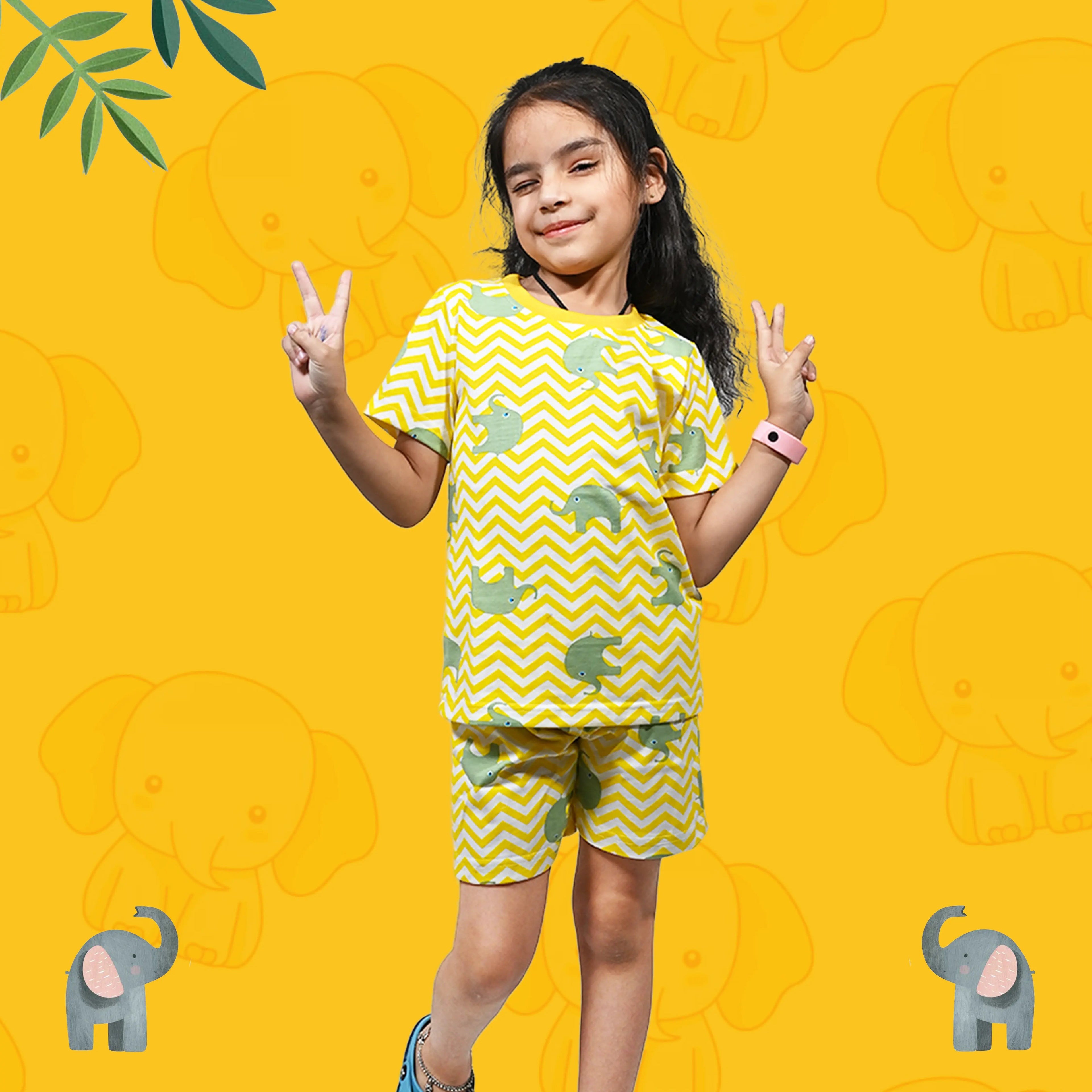 Child wearing a yellow and green patterned outfit on a yellow background with elephant designs.