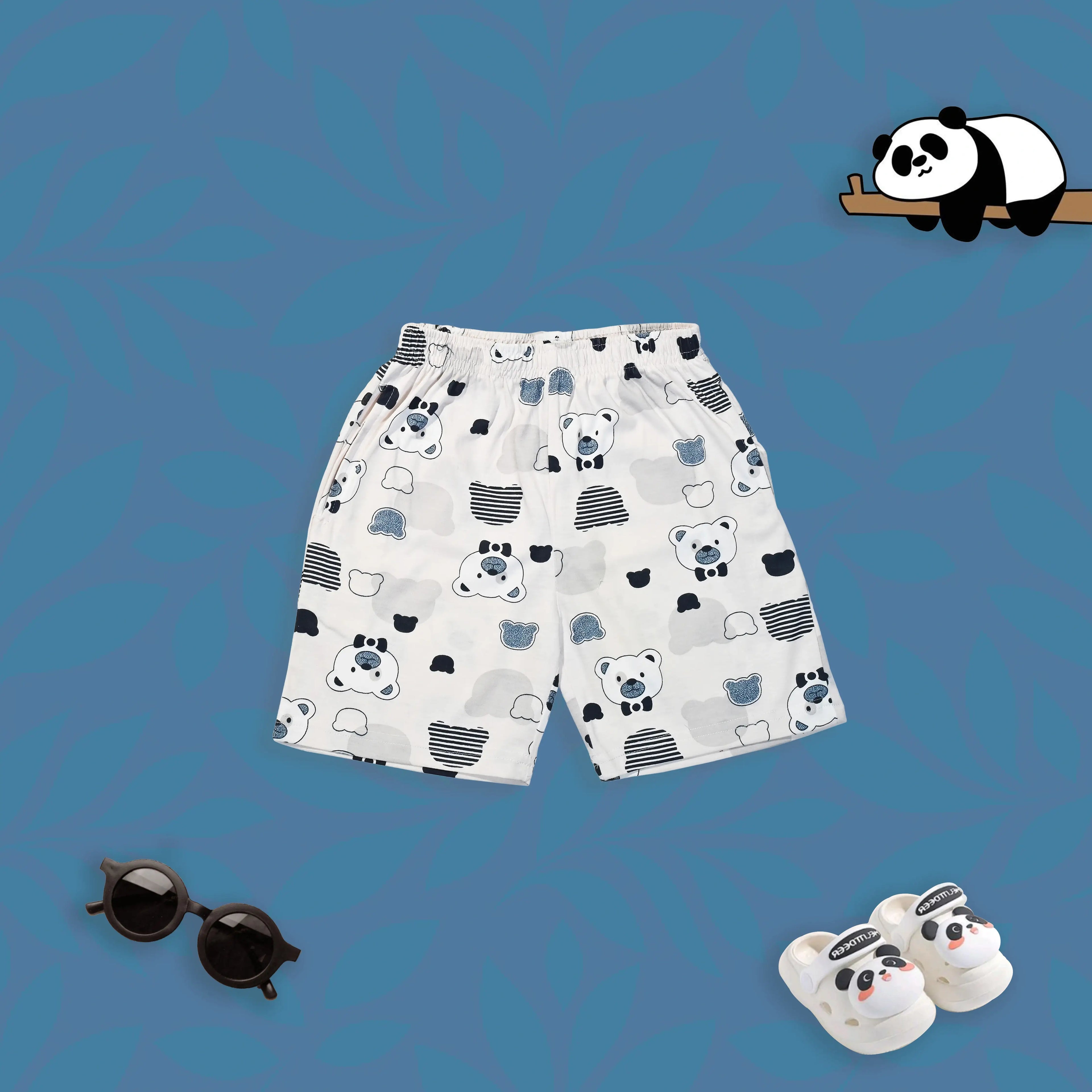 Children's shorts with bear pattern, sunglasses, and panda slippers on a blue background