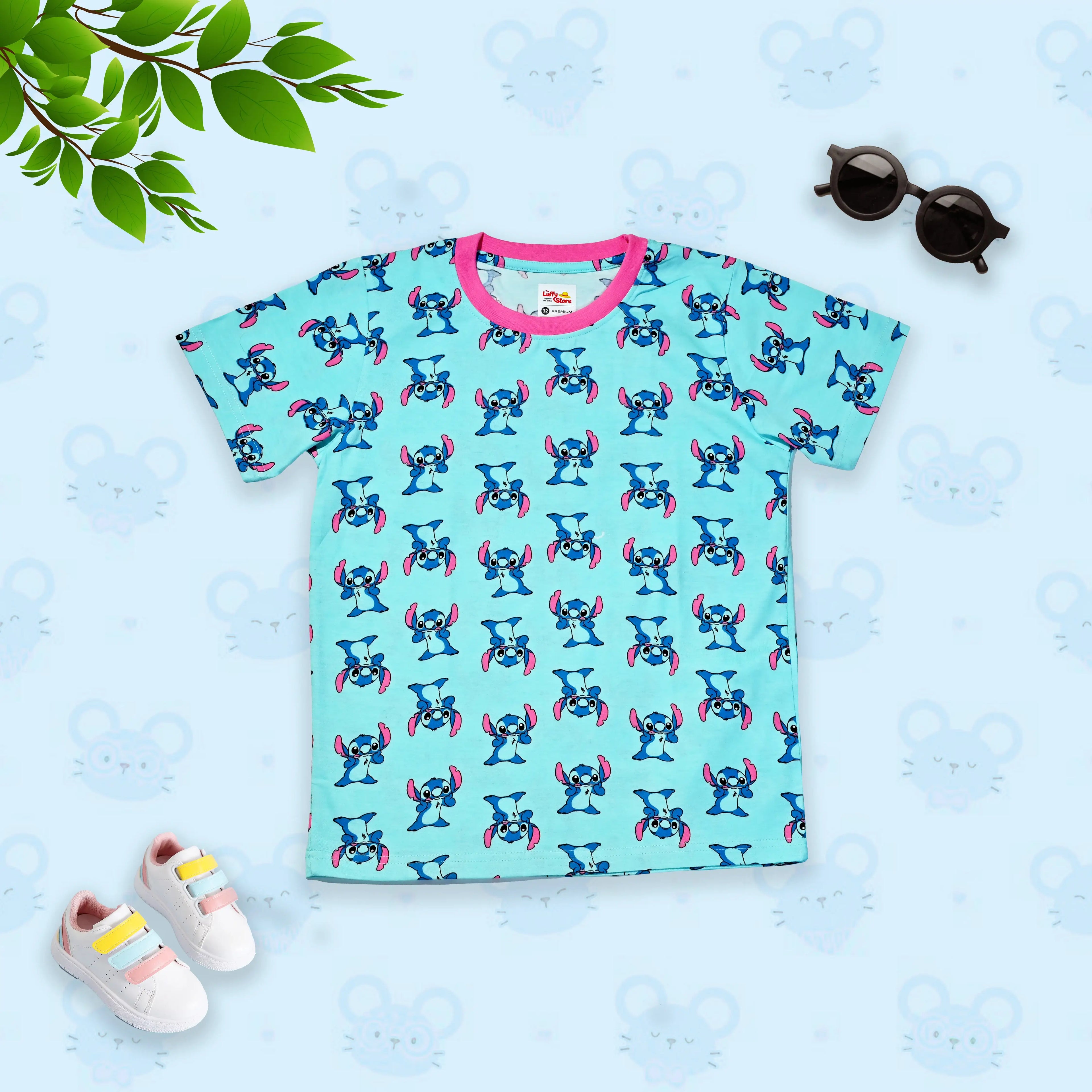 Children's t-shirt with cartoon character pattern on a light blue background, accompanied by shoes and sunglasses.